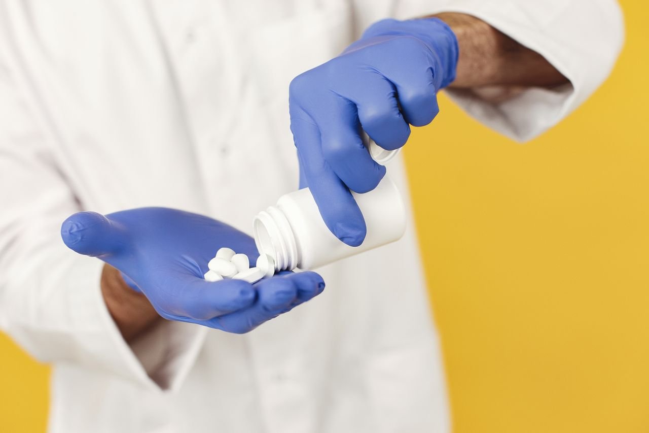 services-img Close-up of a healthcare worker in gloves pouring pills from a bottle.